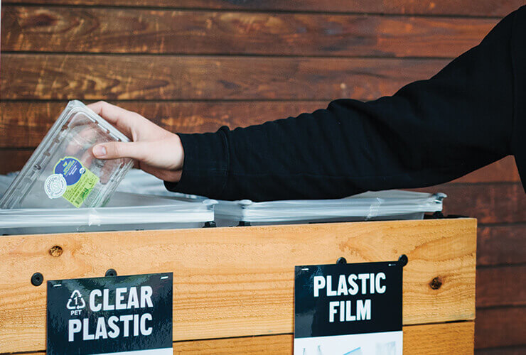 New Seasons Staff member with #1 plastics in front of recycling center 