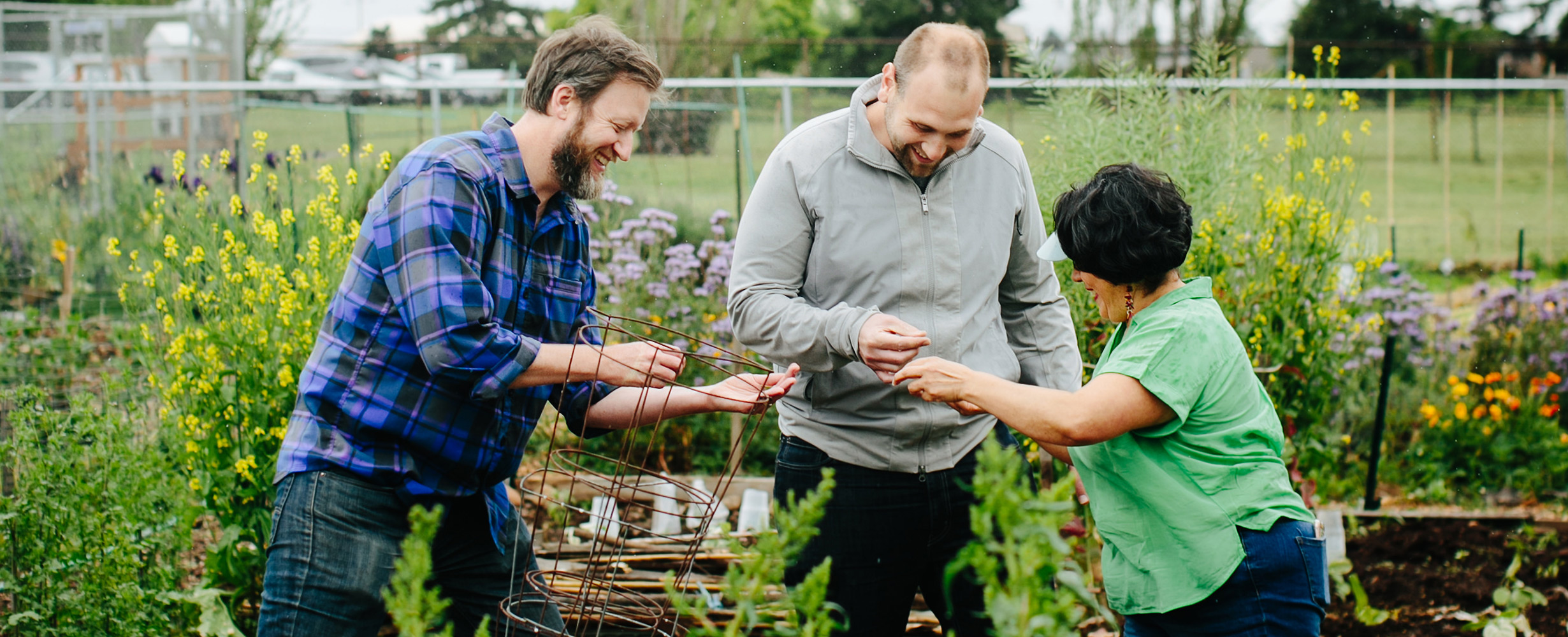 Image from Growing Gardens with people standing in a garden.